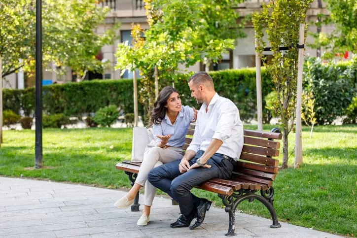 Couple smiling and talking together on a park bench